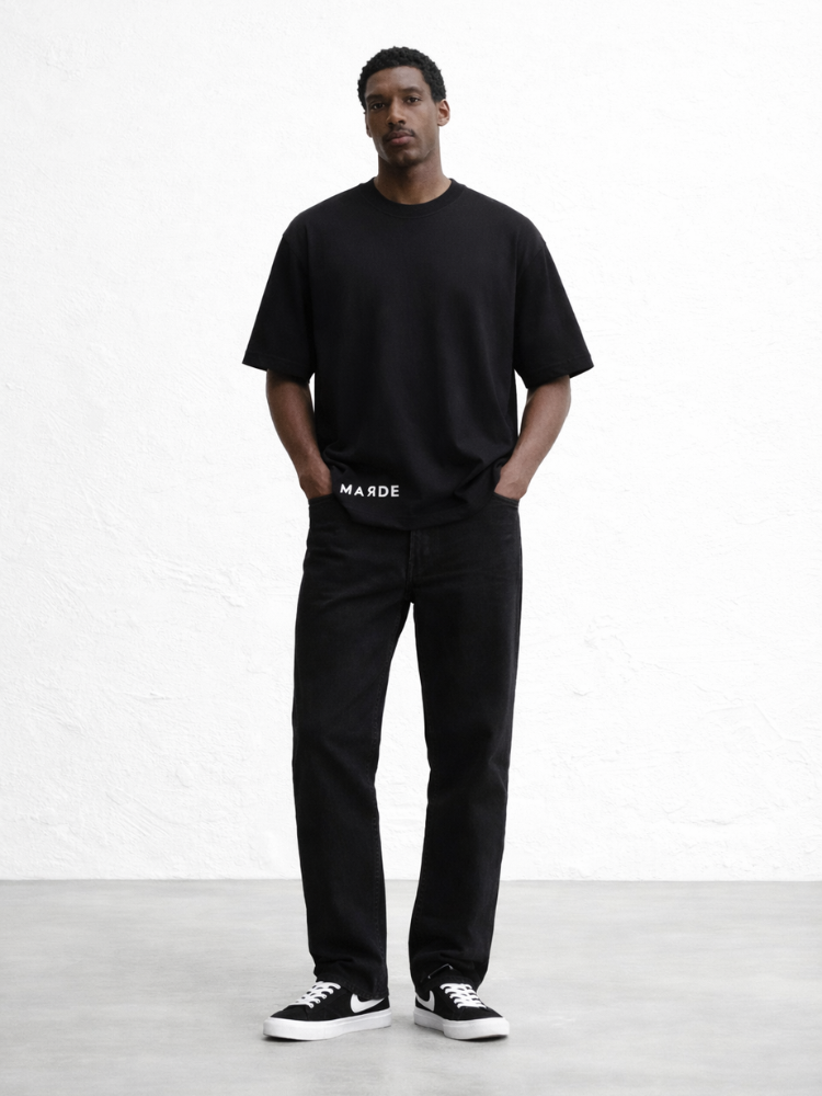 Man wearing a black t-shirt and black pants with white text, standing against a white background