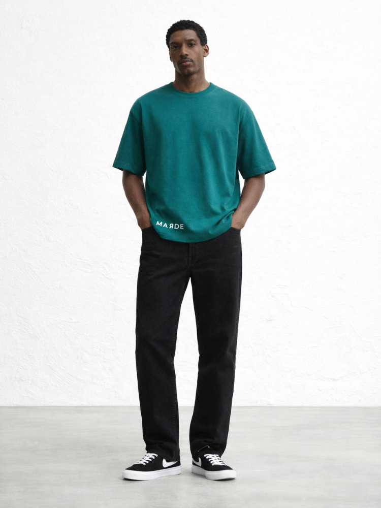 Man wearing a teal t-shirt and black pants on a white background