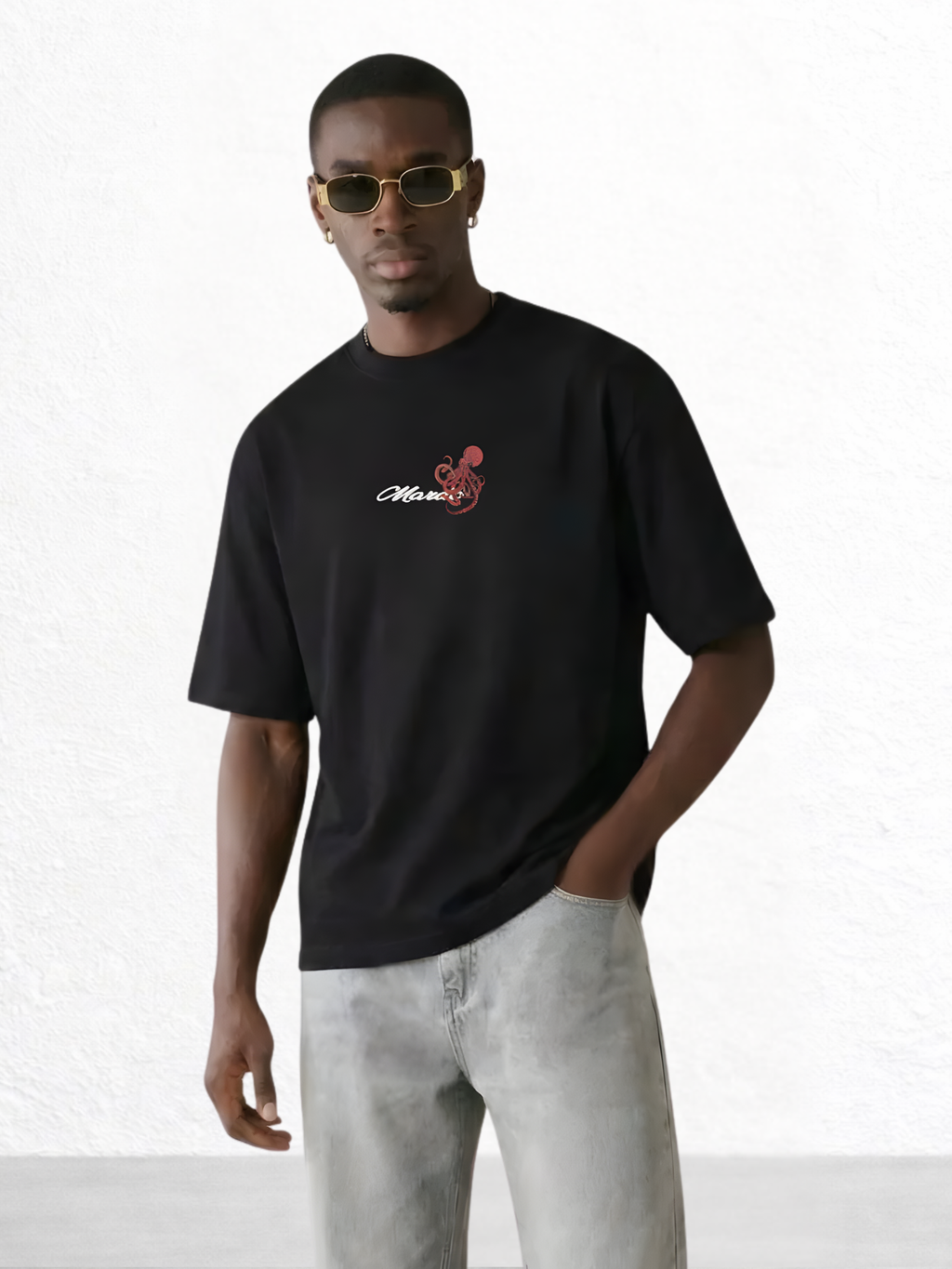 Man wearing a black t-shirt with a logo and sunglasses on a white background