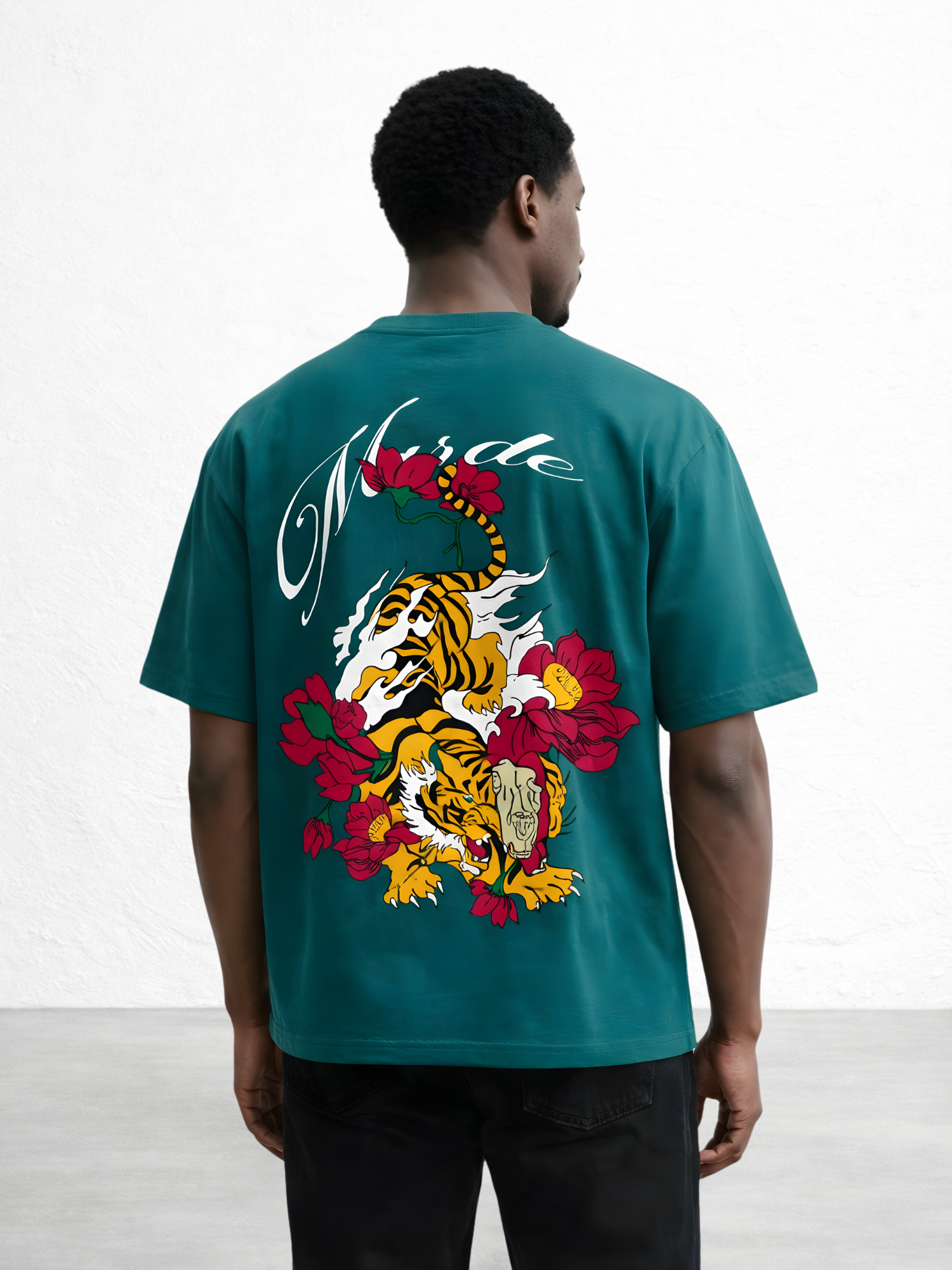 Person wearing a teal t-shirt with a colorful graphic design on the back, standing against a white background.