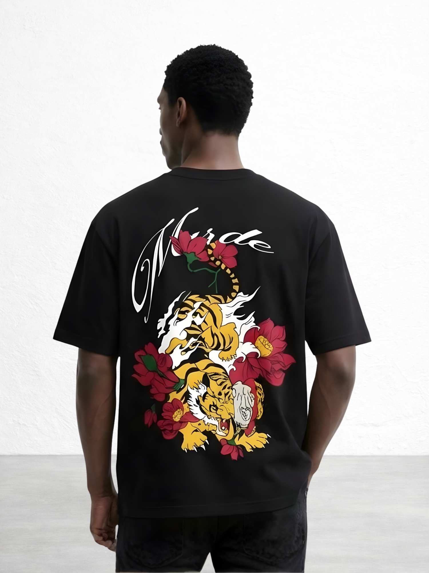 Person wearing a black t-shirt with a tiger and floral design on the back, against a white background.