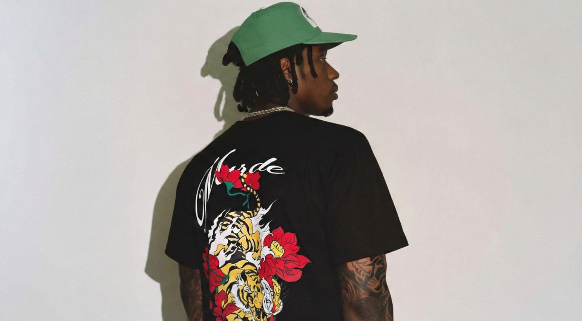 Person wearing a black t-shirt with a colorful design on the back, standing against a plain background.