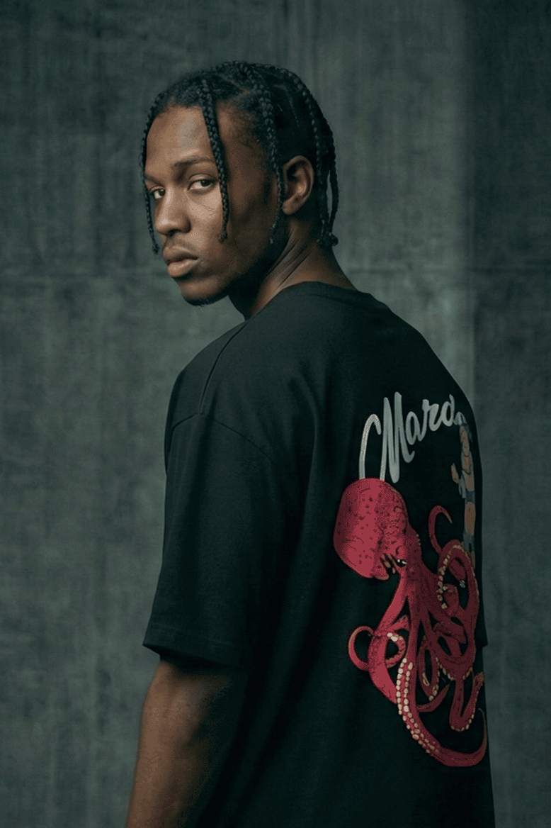 Person wearing a black t-shirt with a red graphic design in a dimly lit room.